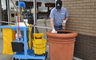 mall maintenance employee cleaning trash from mall parking lot trash can